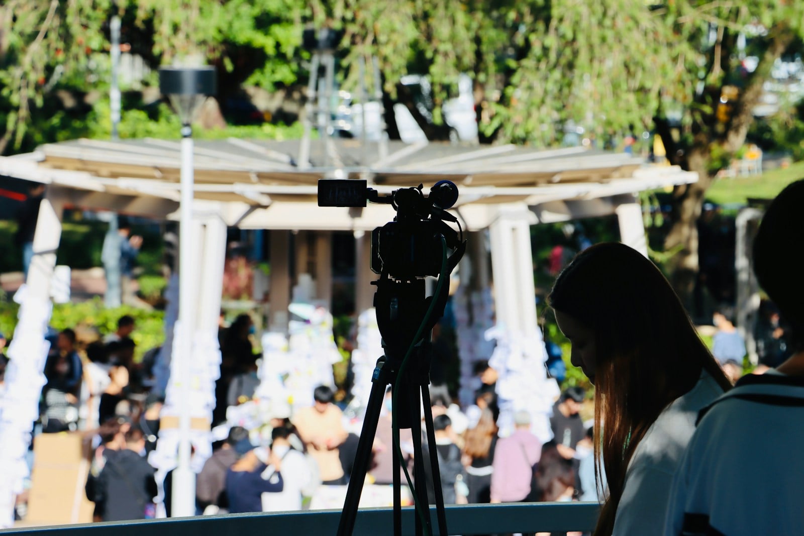 A video camera on a tripod positioned to cover an outdoor event