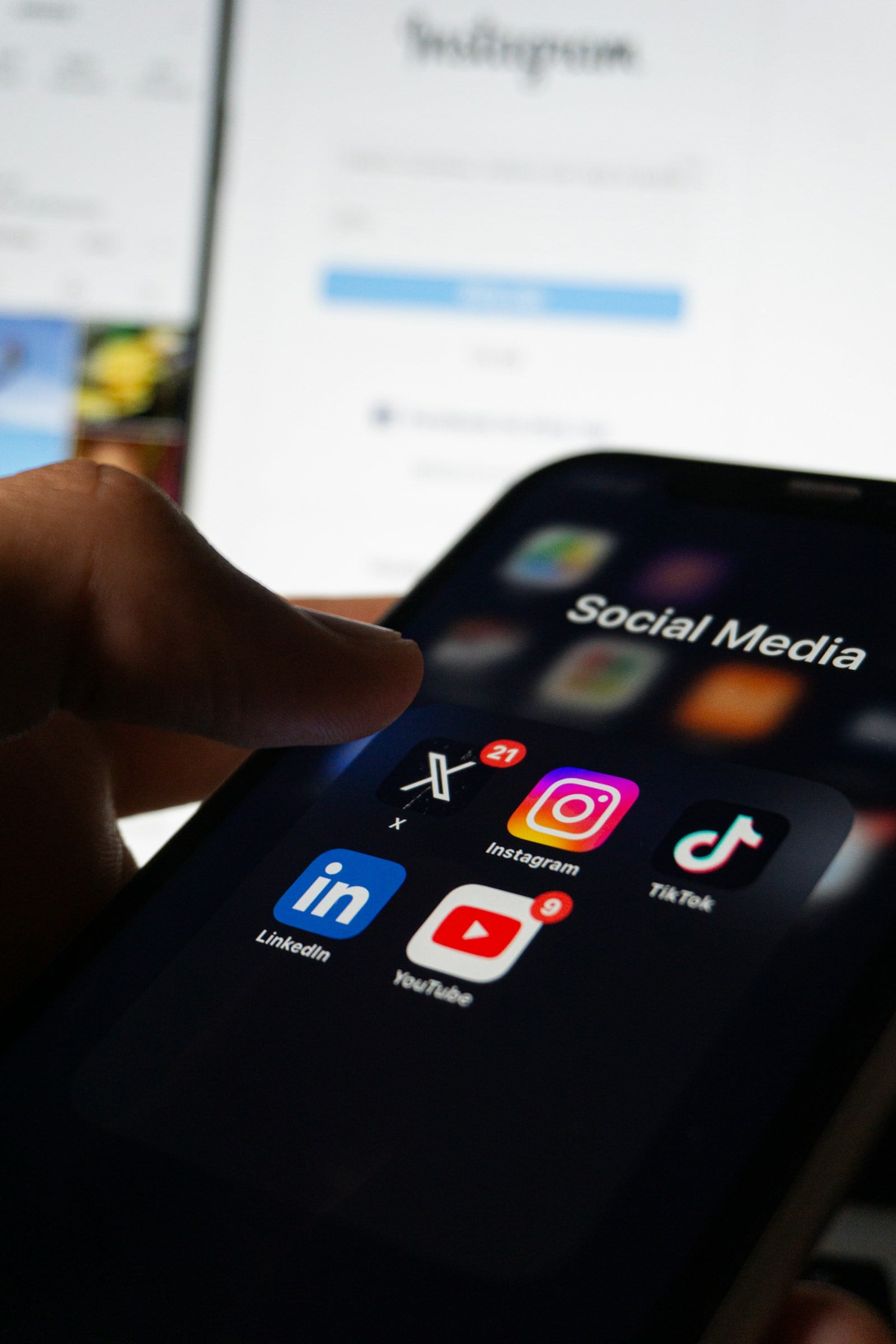 A hand holding a smartphone displaying social media applications